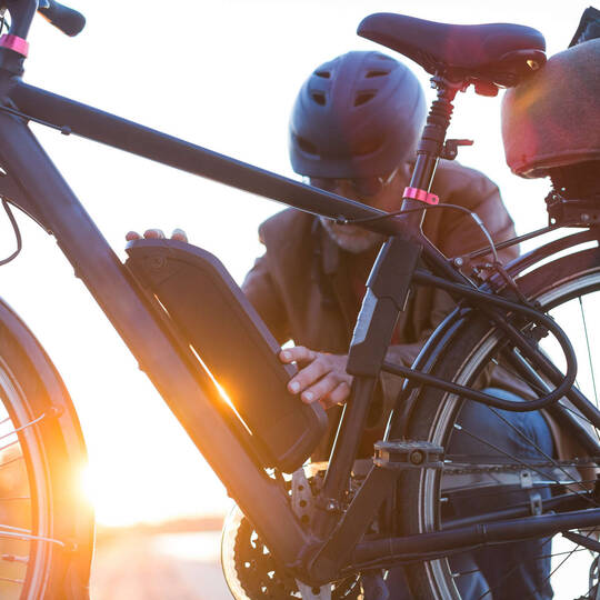 Ein Mann hält die Hände an den Akku eines E-Bikes