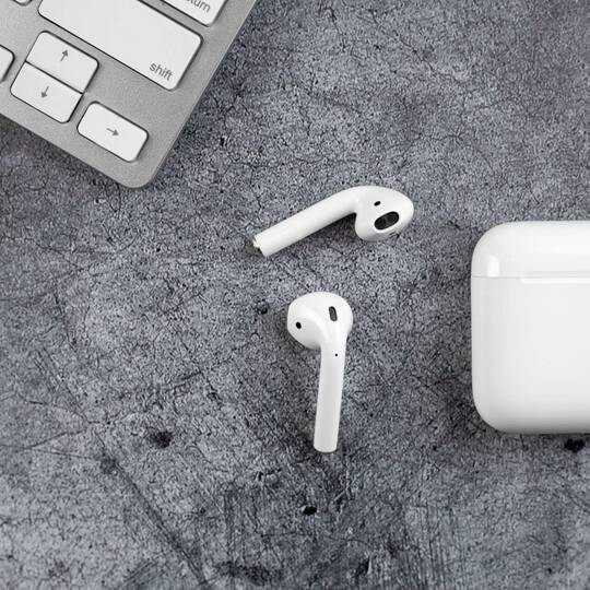 AirPods liegen auf grauer Unterlage